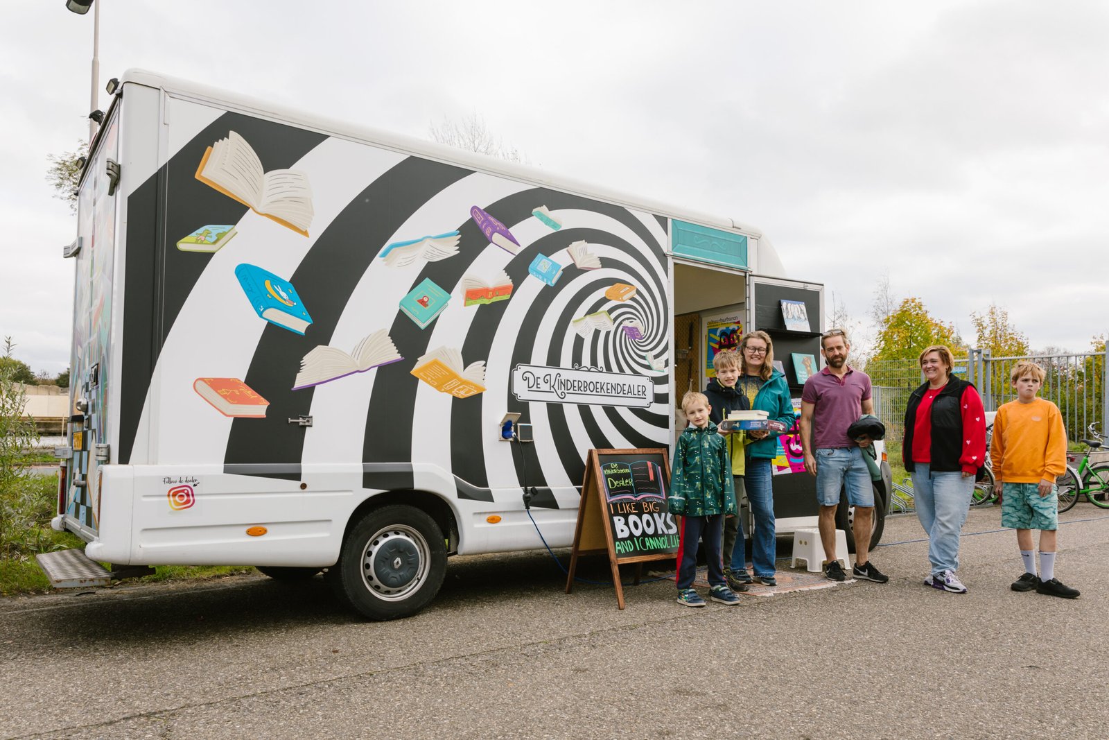 De boekenbus van De Kinderboekendealer tijdens een bezoekmoment, met kinderen en volwassenen die boeken bekijken bij de rijdende kinderboekenwinkel.